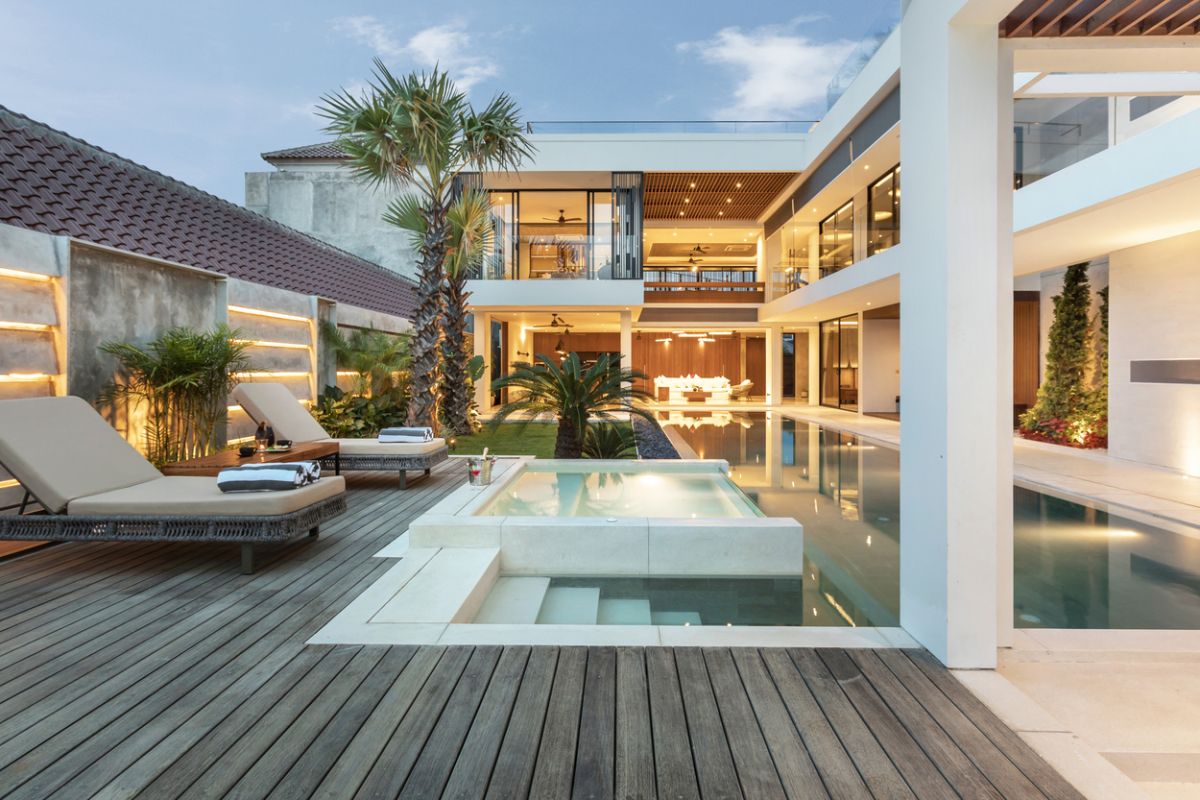 Elegant outdoor dining table set for dinner in a luxurious Bali villa, with tropical plants, pool view, and NVYL branding at night. - Bali Villas