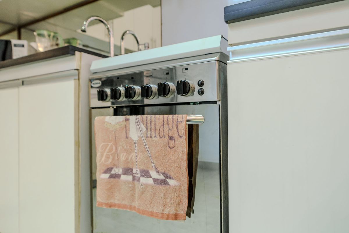 Modern living room with wooden wall panels, orange patterned sofa, Netflix on wall-mounted TV, abstract wall art, and potted plants. - Bali Villas