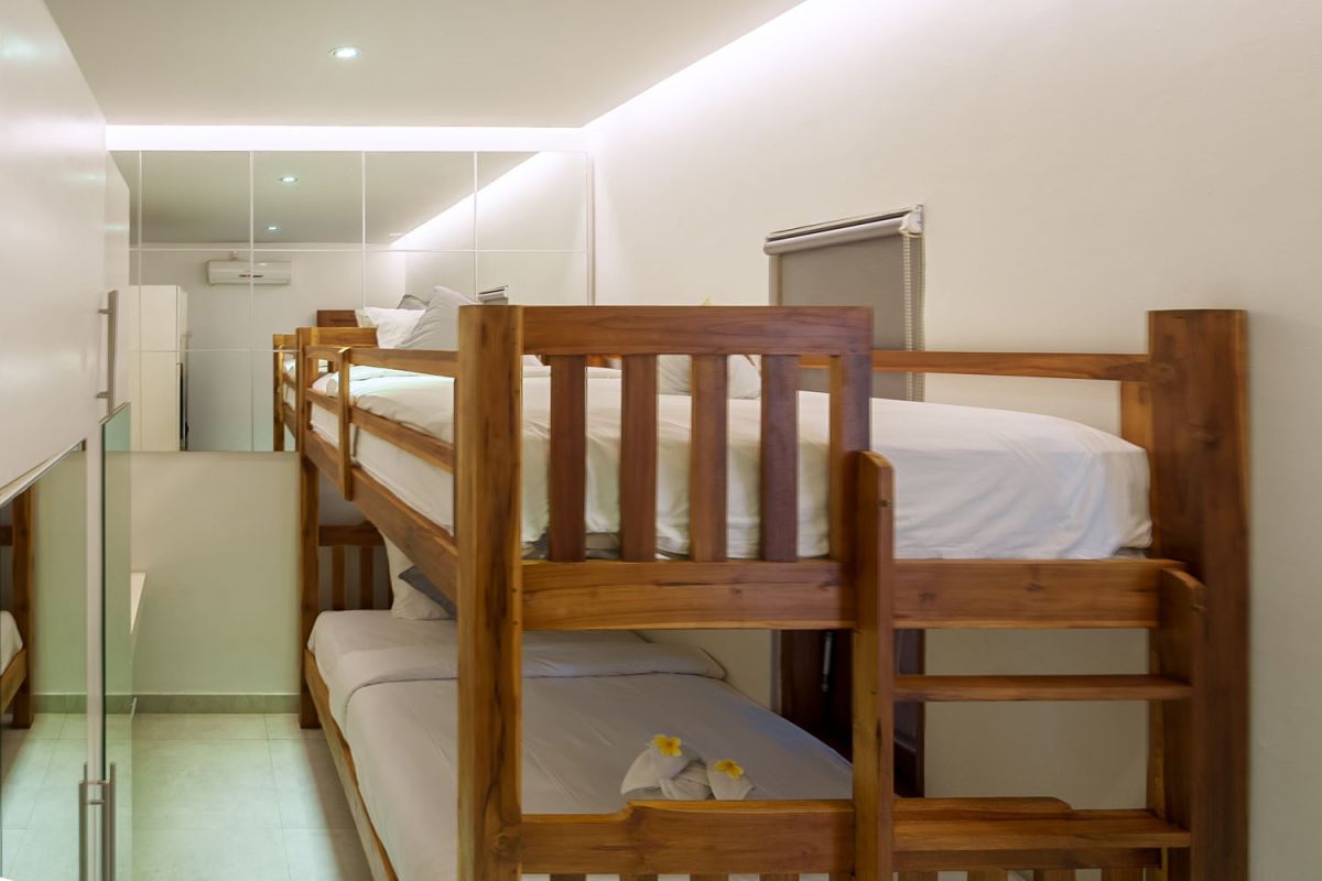 Modern living room with wooden wall panels, orange patterned sofa, Netflix on wall-mounted TV, abstract wall art, and potted plants. - Bali Villas
