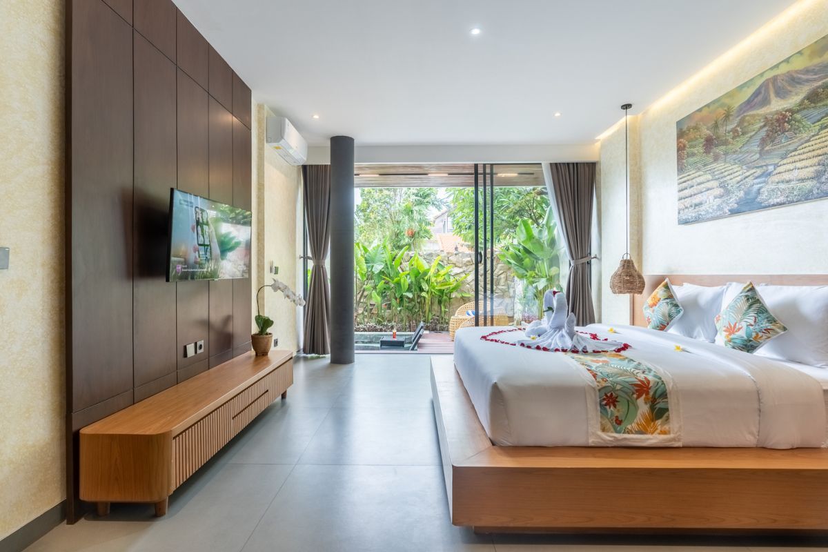 Modern wooden pool table in a spacious tropical living room with large windows, plants, and cozy seating. - Bali Villas