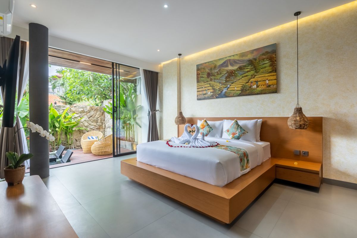 Modern wooden pool table in a spacious tropical living room with large windows, plants, and cozy seating. - Bali Villas
