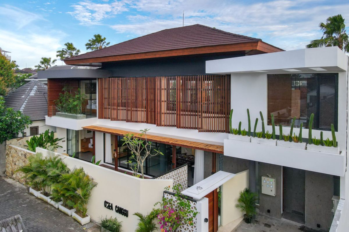 Modern wooden pool table in a spacious tropical living room with large windows, plants, and cozy seating. - Bali Villas