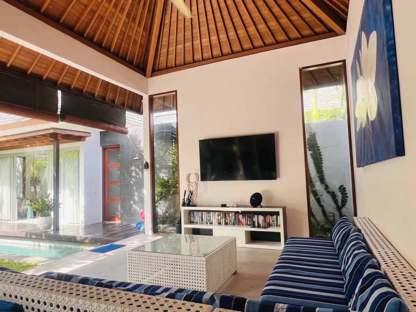 Serene Balinese villa pool with turquoise water, white lounge chairs, frangipani trees, and lush tropical greenery under a blue sky. - Bali Villas