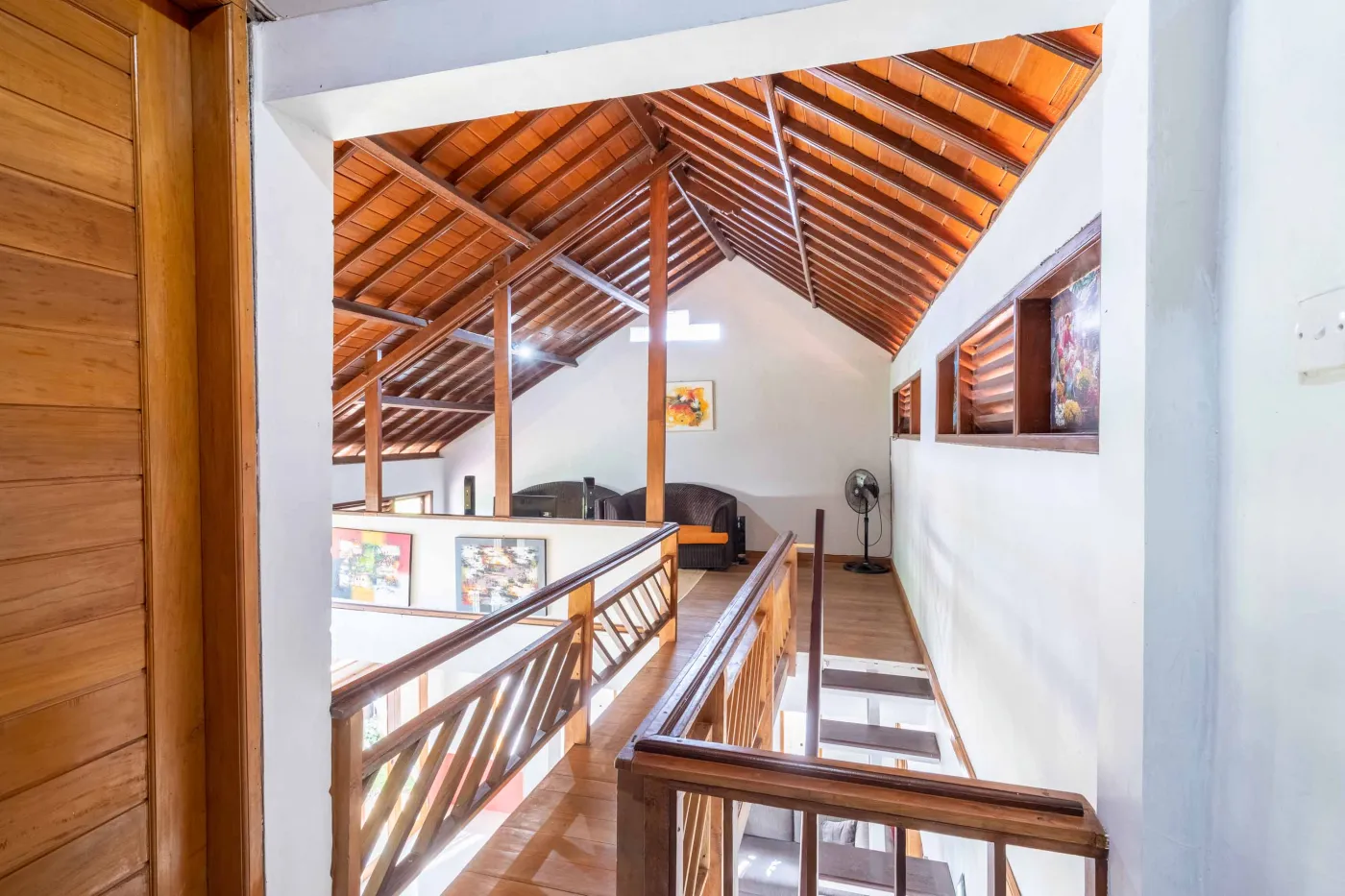 Rustic Balinese kitchen with wooden cabinets, blue range hood, mosaic tiled backsplash, black fridge, and ceiling fan. - Bali Villas