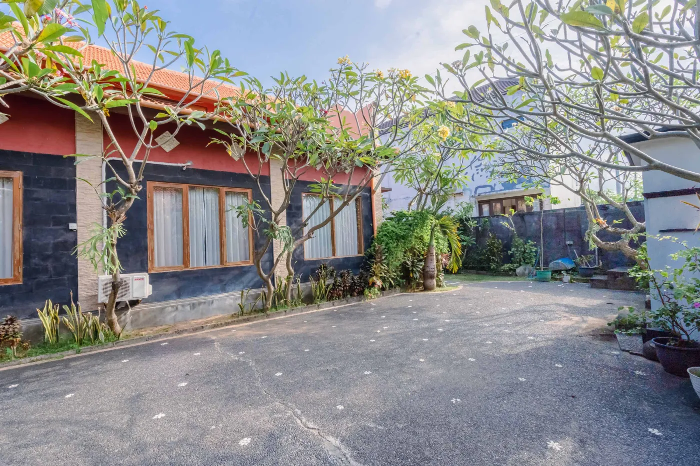 Rustic Balinese kitchen with wooden cabinets, blue range hood, mosaic tiled backsplash, black fridge, and ceiling fan. - Bali Villas