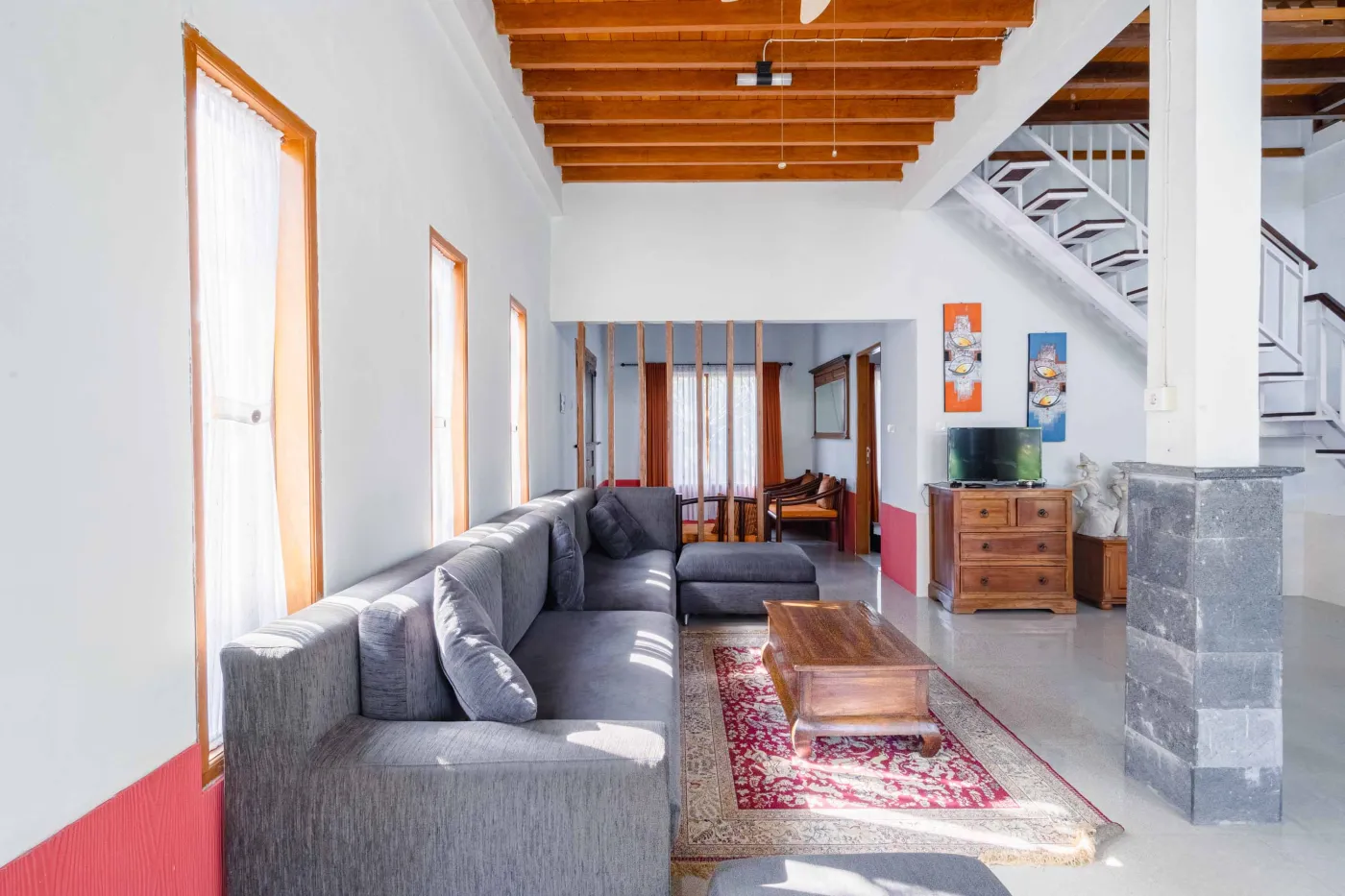 Rustic Balinese kitchen with wooden cabinets, blue range hood, mosaic tiled backsplash, black fridge, and ceiling fan. - Bali Villas