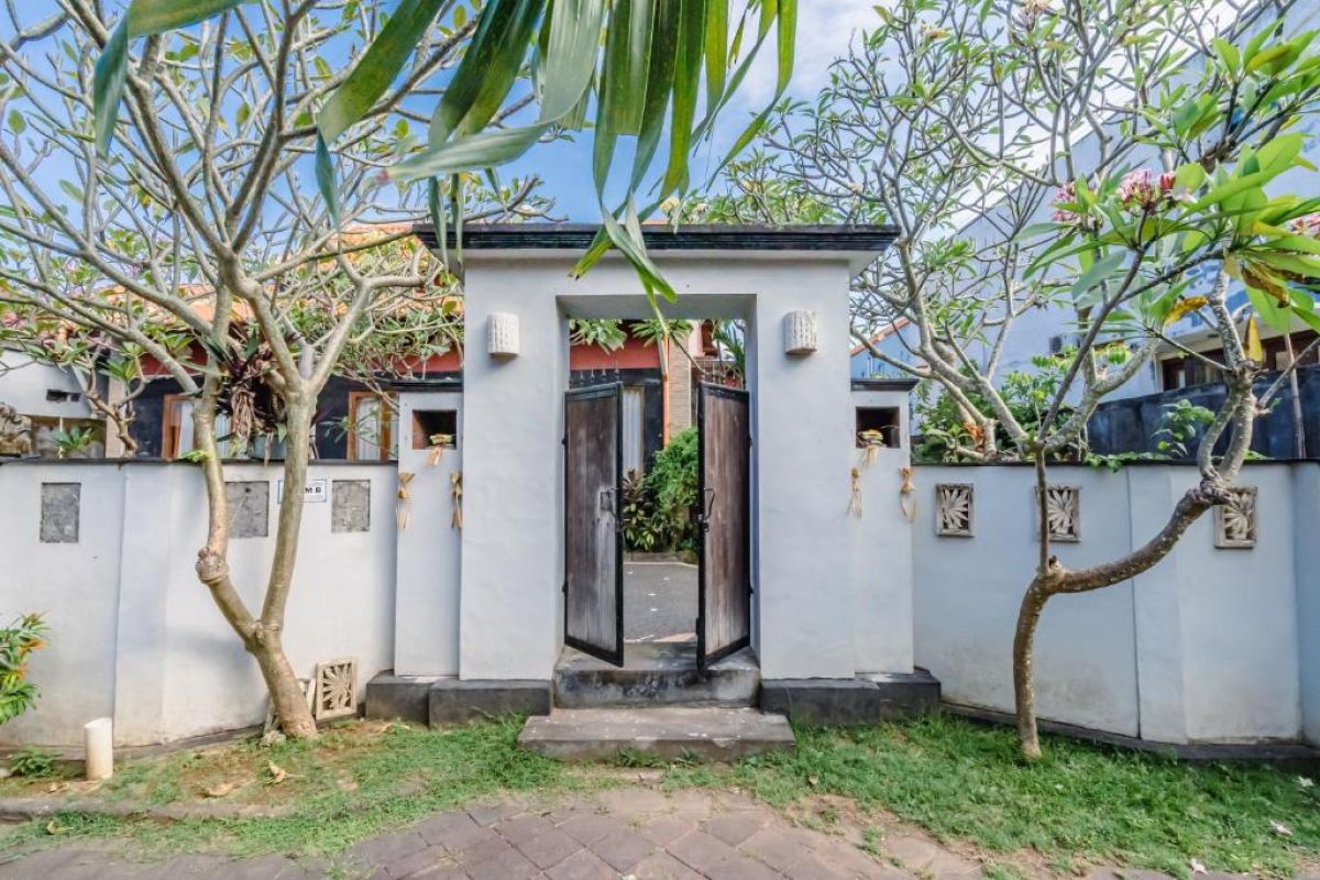 Rustic wooden kitchen with black fridge, gas stove, sink, glass-door cabinets, teal hood, and tiled backsplash. - Bali Villas
