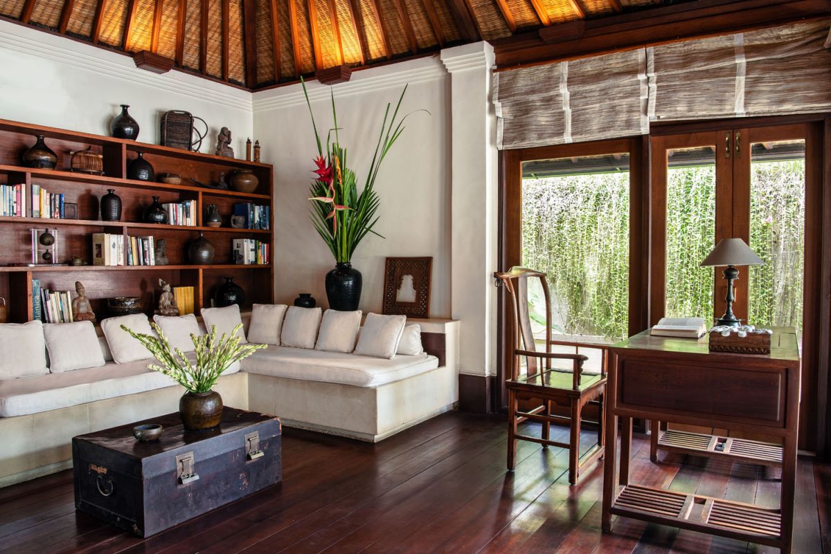 Serene Balinese villa courtyard with koi pond, stone steps, lush tropical plants, and palm trees under a clear sky. - Bali Villas