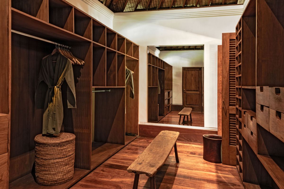 Serene Balinese villa courtyard with koi pond, stone steps, lush tropical plants, and palm trees under a clear sky. - Bali Villas