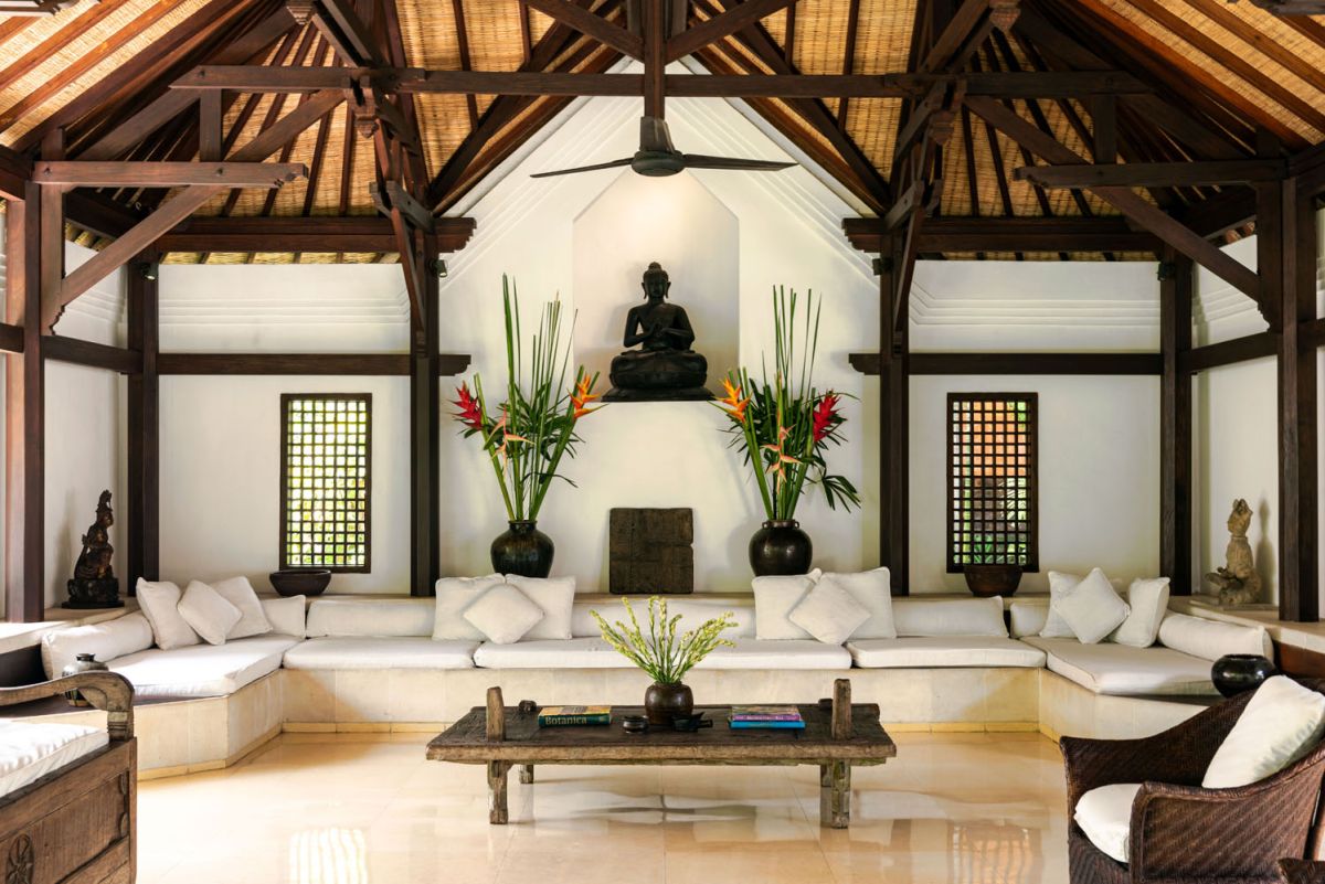 Serene Balinese villa courtyard with koi pond, stone steps, lush tropical plants, and palm trees under a clear sky. - Bali Villas