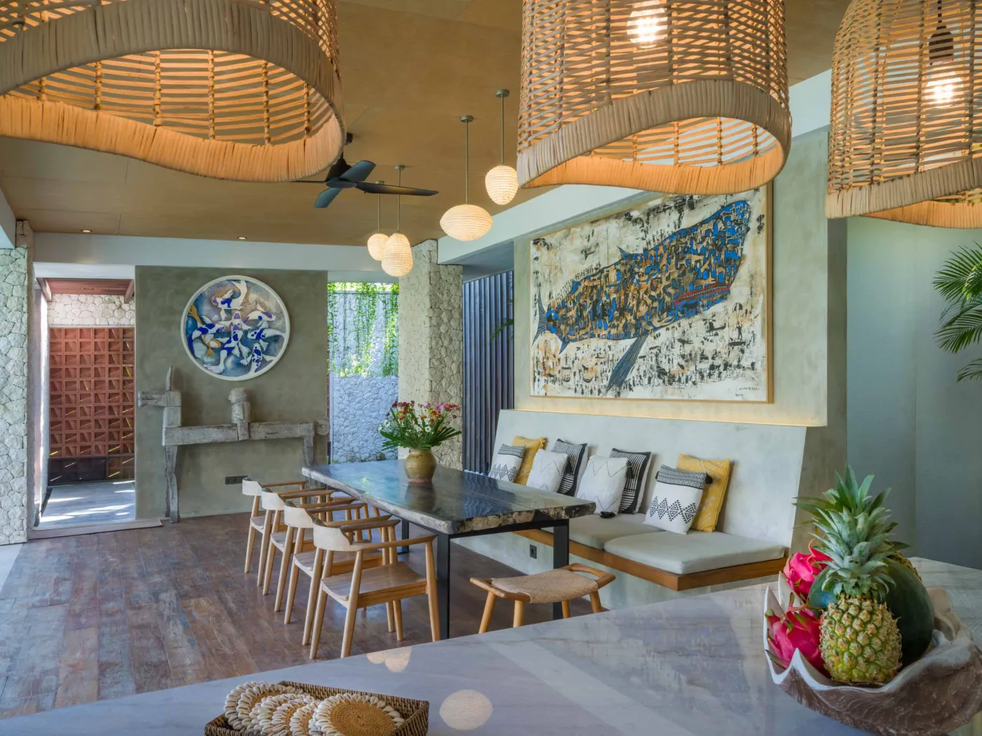 Luxurious open-air Balinese bathroom with freestanding bathtub filled with rose petals, wooden vanity, tropical plants, and geometric tiled floor. - Bali Villas
