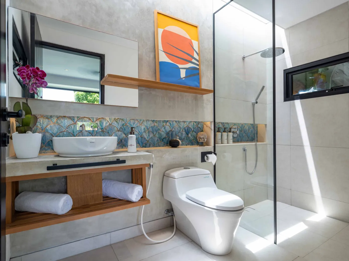 Luxurious open-air Balinese bathroom with freestanding bathtub filled with rose petals, wooden vanity, tropical plants, and geometric tiled floor. - Bali Villas