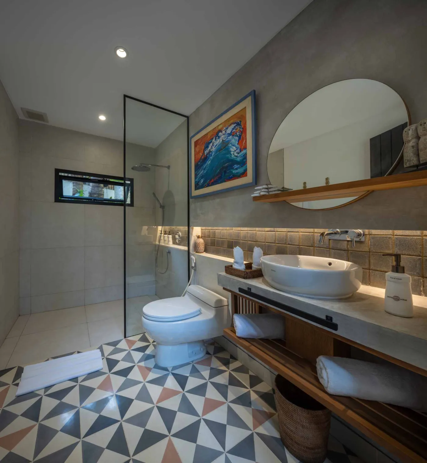 Luxurious open-air Balinese bathroom with freestanding bathtub filled with rose petals, wooden vanity, tropical plants, and geometric tiled floor. - Bali Villas