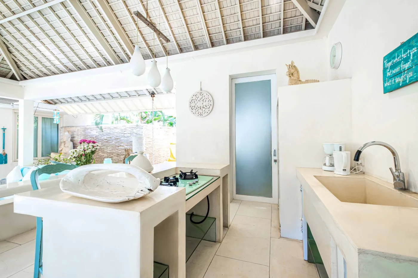 Modern luxury bedroom suite with white platform bed, teal pillow, turquoise sunken bathtub, and garden view through sheer curtains. - Bali Villas