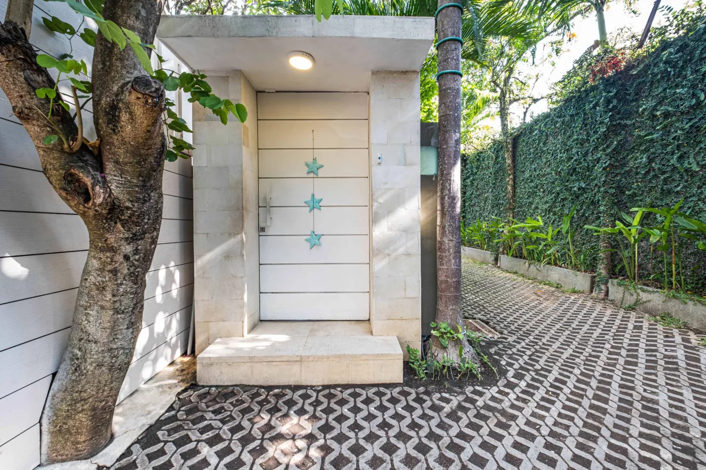 Modern luxury bedroom suite with white platform bed, teal pillow, turquoise sunken bathtub, and garden view through sheer curtains. - Bali Villas