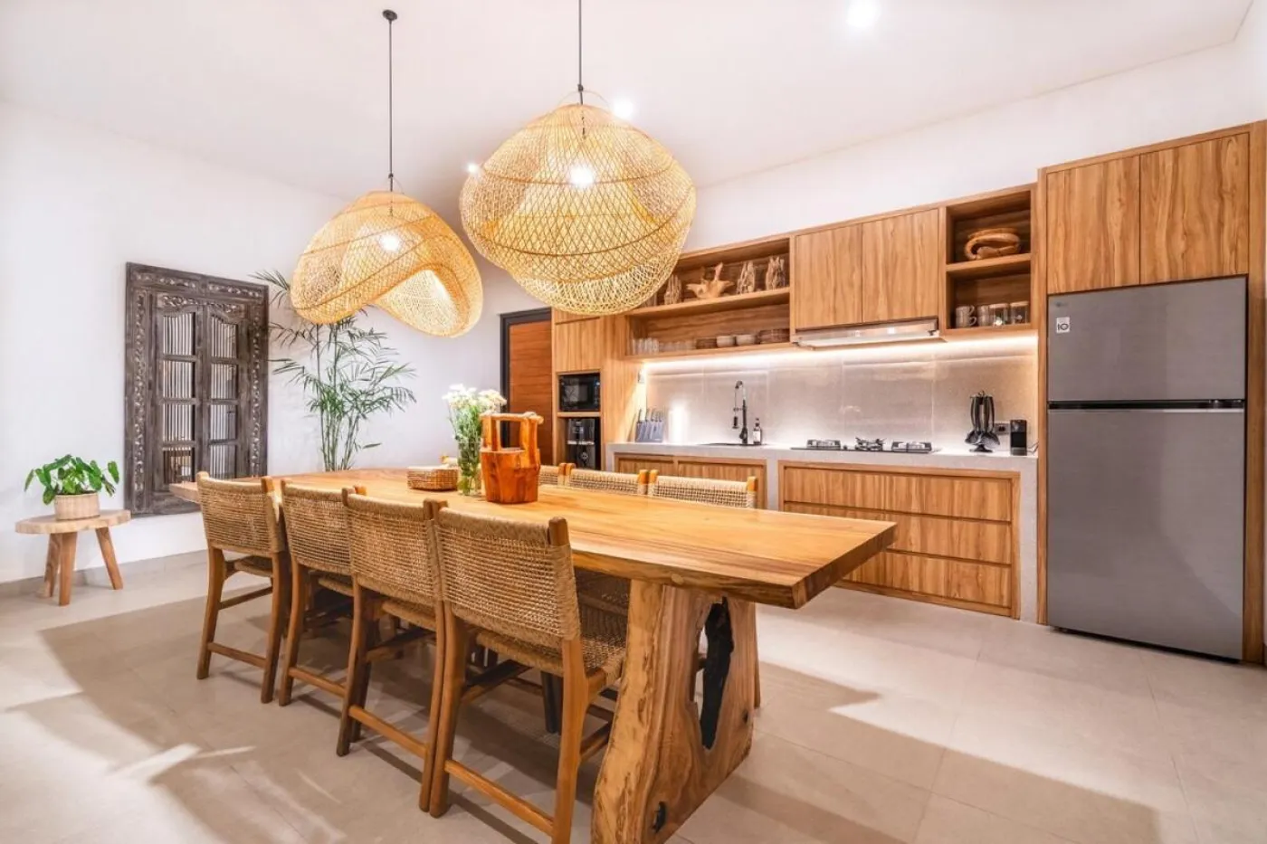 Compact modern bathroom with white toilet, tall potted plant, small shelf of toiletries, and beige walls. - Bali Villas