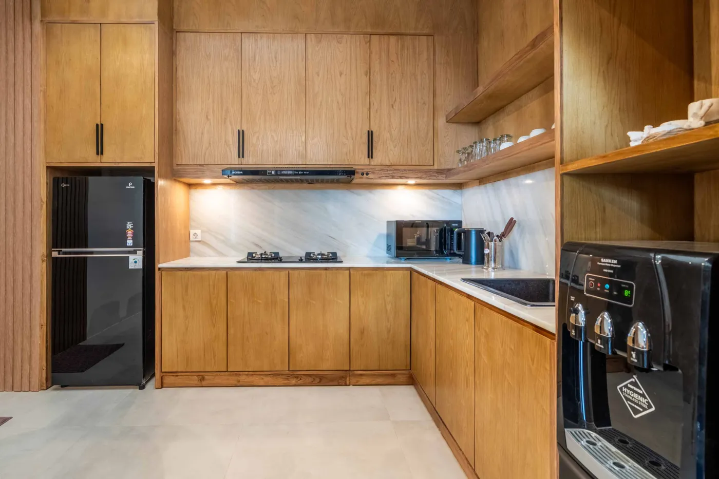 Modern wooden deck balcony with beige sofa, teak table, and chairs, overlooking contemporary rooftops on a sunny day. - Bali Villas