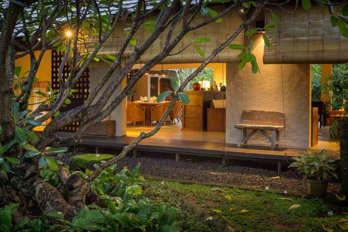 Modern luxury bathroom with freestanding white bathtub, glass shower enclosure, towels, and tropical plant accents. - Bali Villas