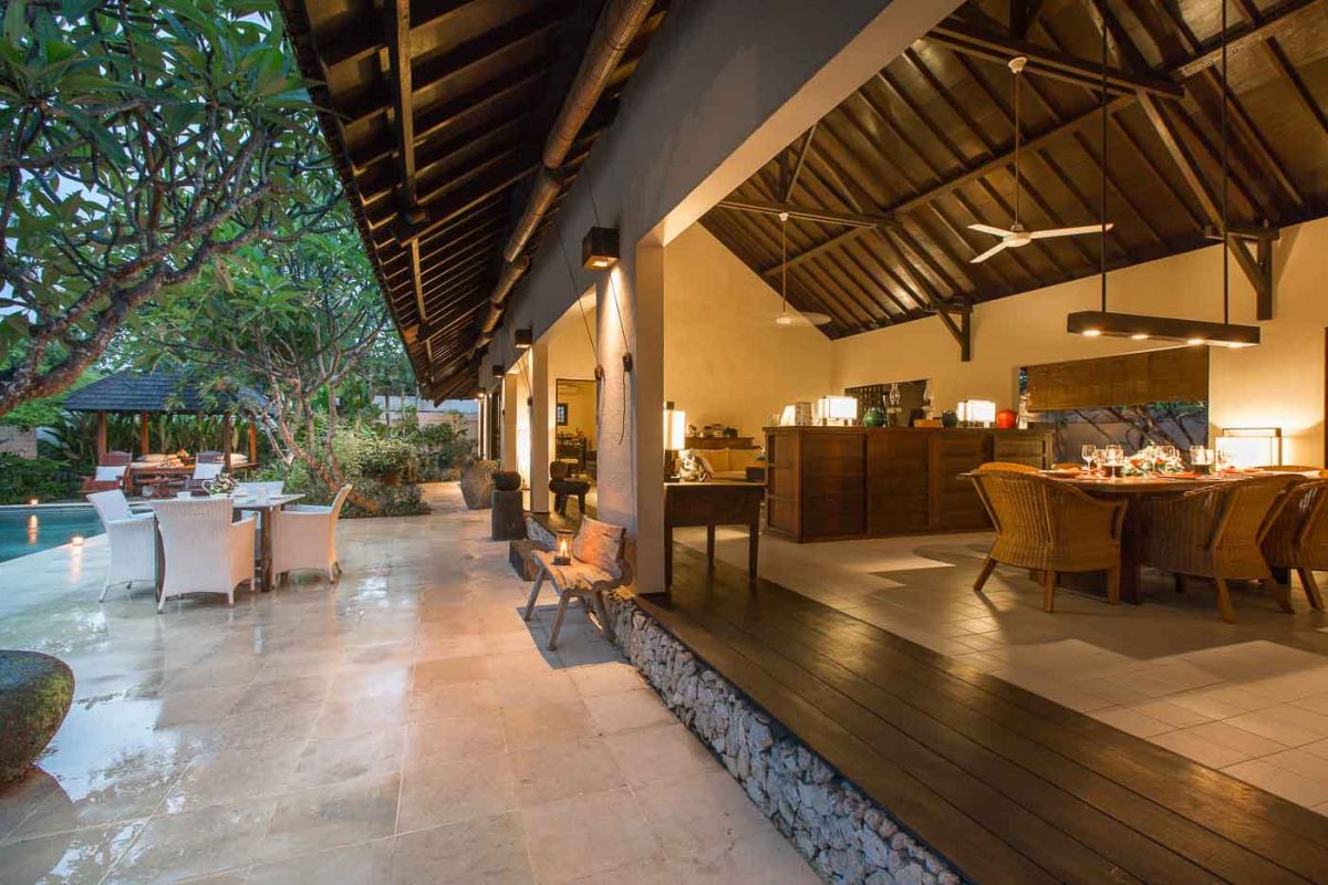 Modern luxury bathroom with freestanding white bathtub, glass shower enclosure, towels, and tropical plant accents. - Bali Villas