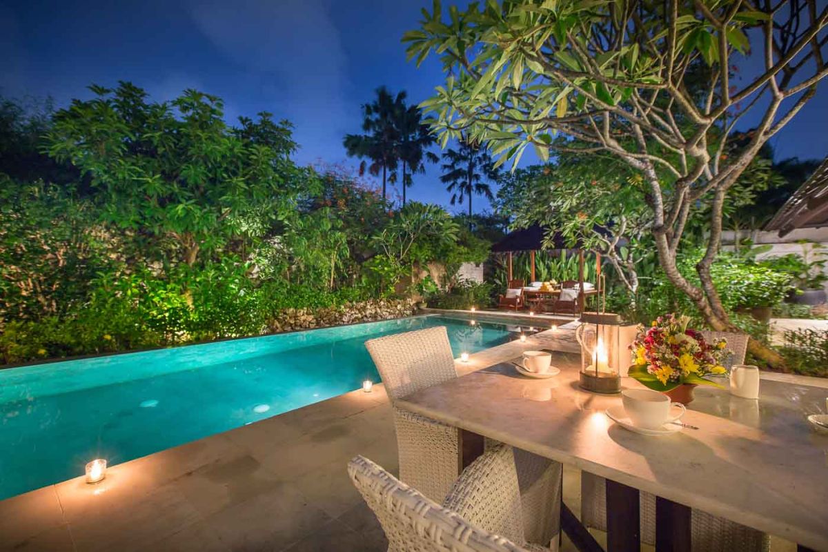 Modern luxury bathroom with freestanding white bathtub, glass shower enclosure, towels, and tropical plant accents. - Bali Villas