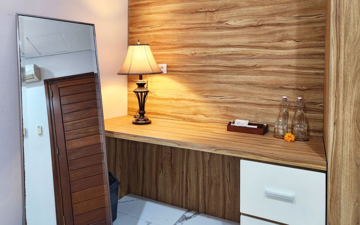 Modern open-plan kitchen and dining area with wooden cabinets, marble-top table, stainless steel fridge, and potted orchids in a Balinese villa. - Bali Villas