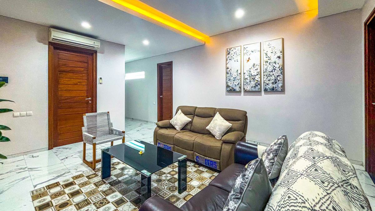 Modern open-plan kitchen and dining area with wooden cabinets, marble-top table, stainless steel fridge, and potted orchids in a Balinese villa. - Bali Villas