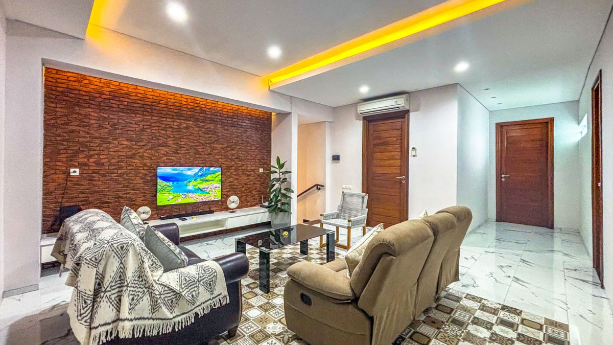 Modern open-plan kitchen and dining area with wooden cabinets, marble-top table, stainless steel fridge, and potted orchids in a Balinese villa. - Bali Villas