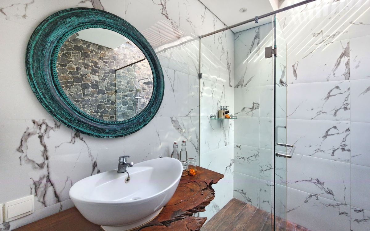 Modern open-plan kitchen and dining area with wooden cabinets, marble-top table, stainless steel fridge, and potted orchids in a Balinese villa. - Bali Villas