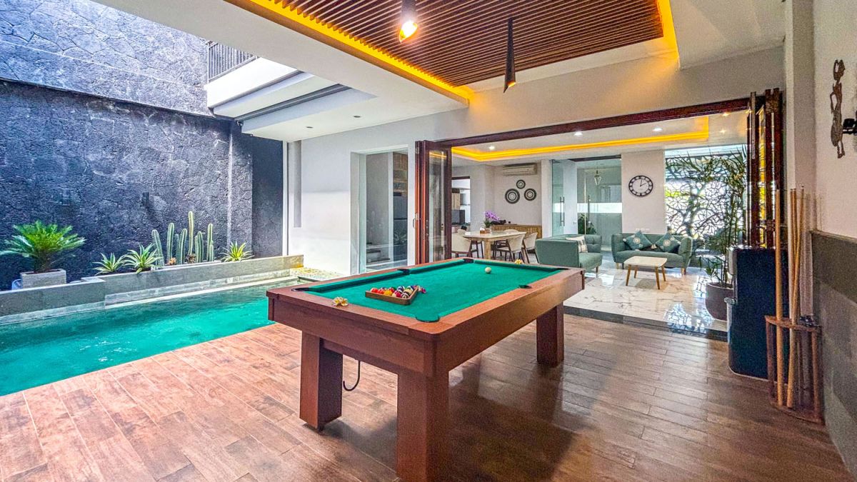 Modern open-plan kitchen and dining area with wooden cabinets, marble-top table, stainless steel fridge, and potted orchids in a Balinese villa. - Bali Villas