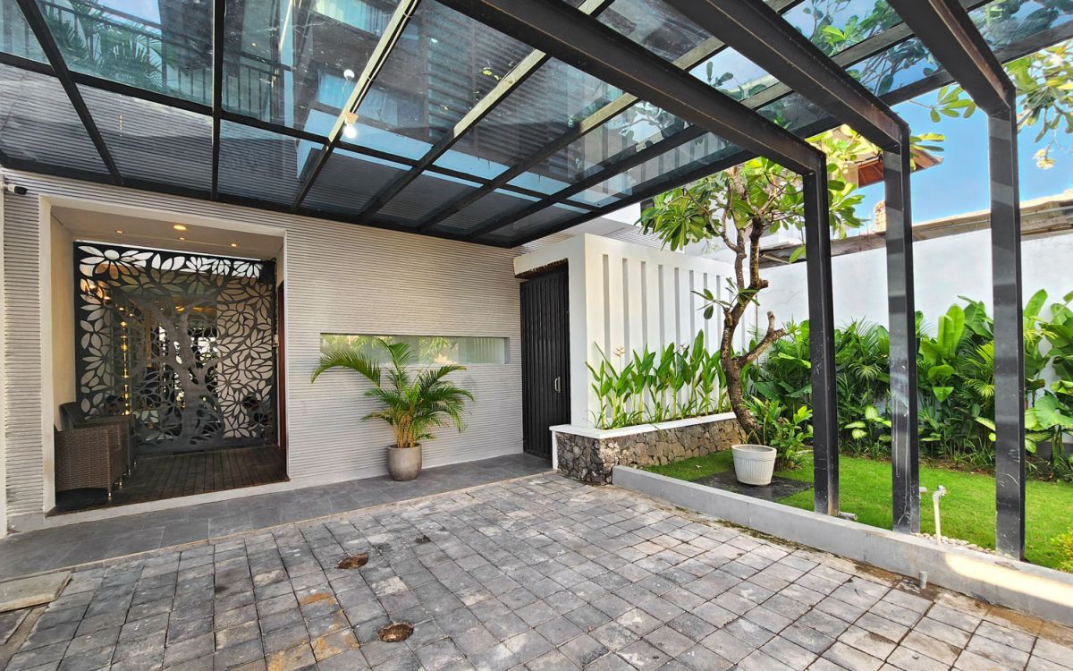 Modern open-plan kitchen and dining area with wooden cabinets, marble-top table, stainless steel fridge, and potted orchids in a Balinese villa. - Bali Villas