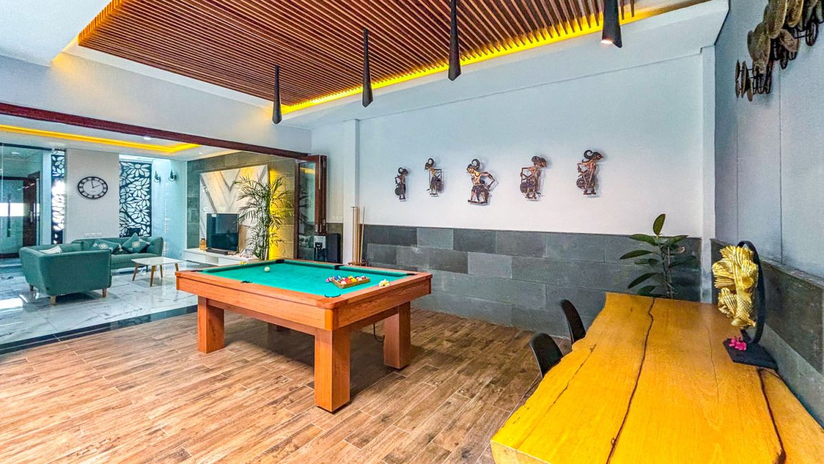 Modern open-plan kitchen and dining area with wooden cabinets, marble-top table, stainless steel fridge, and potted orchids in a Balinese villa. - Bali Villas