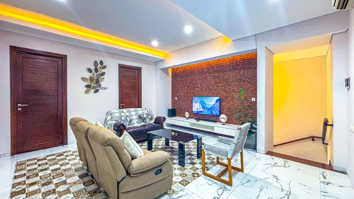 Modern open-plan kitchen and dining area with wooden cabinets, marble-top table, stainless steel fridge, and potted orchids in a Balinese villa. - Bali Villas
