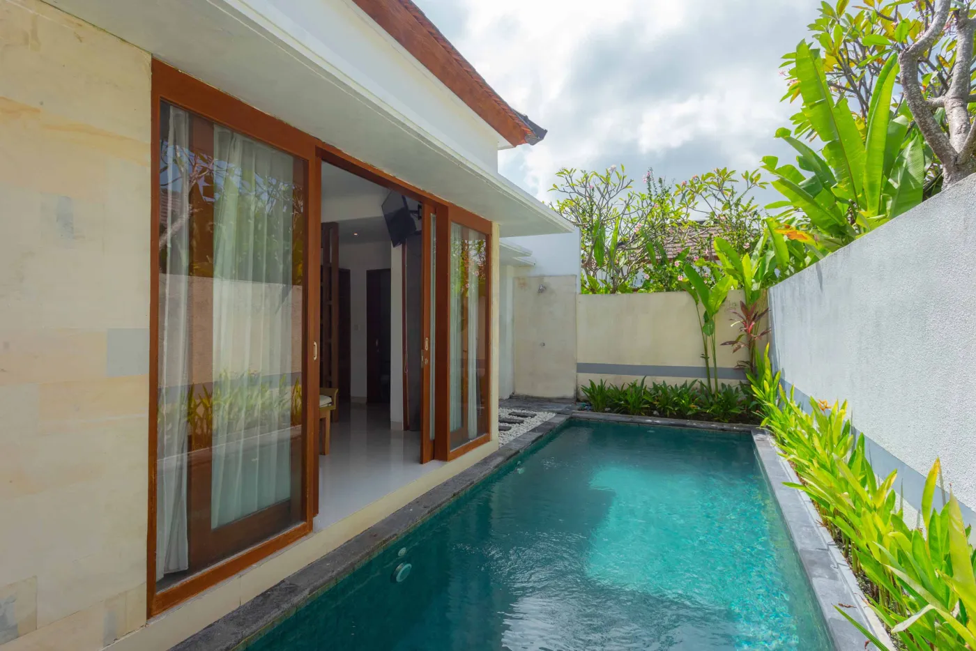 Luxurious tropical bedroom with king bed and sliding glass doors opening to a private plunge pool. - Bali Villas