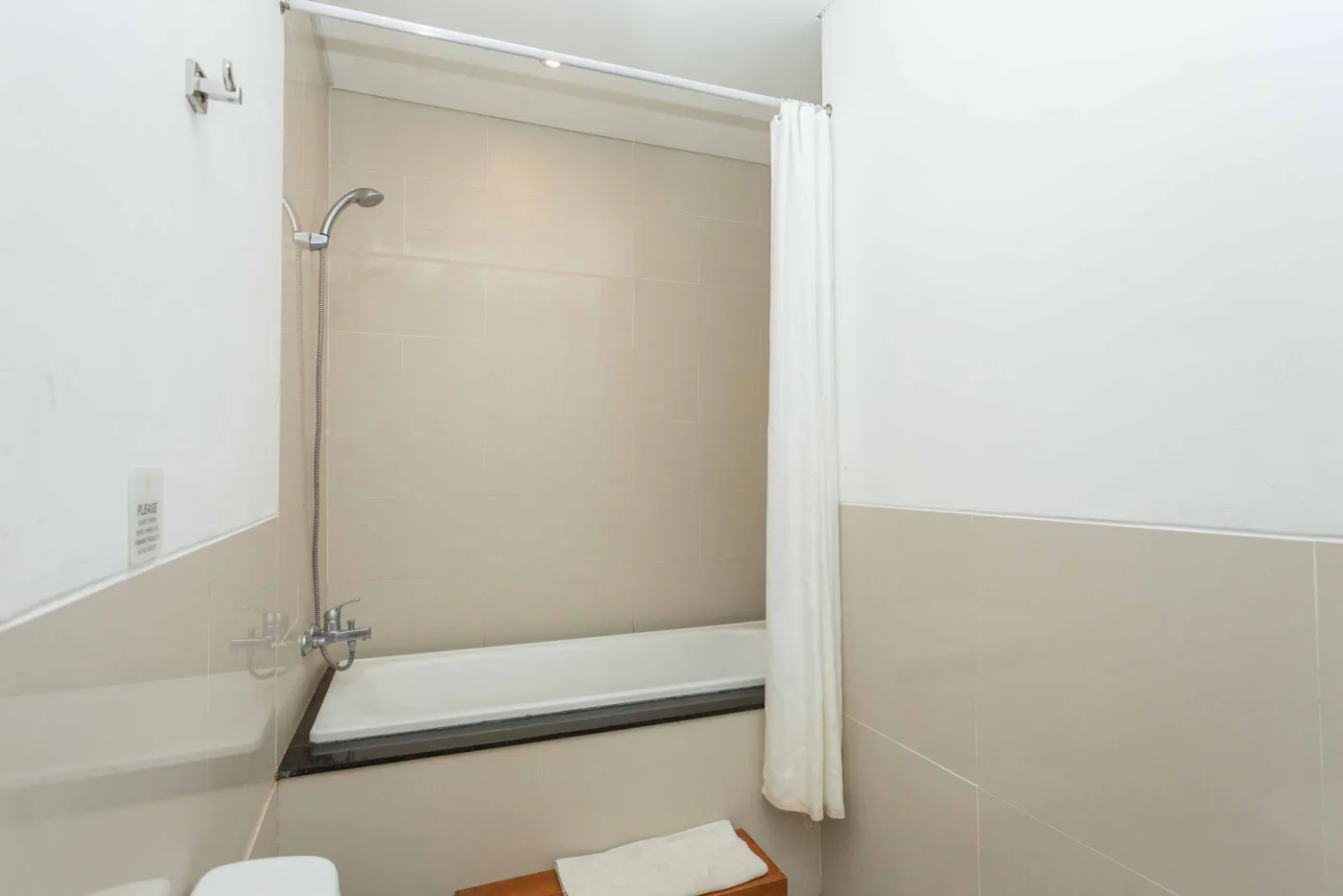 Spacious tropical villa interior with wooden dining table, cushioned sofa, ceiling fan, round mirror, and open deck. - Bali Villas