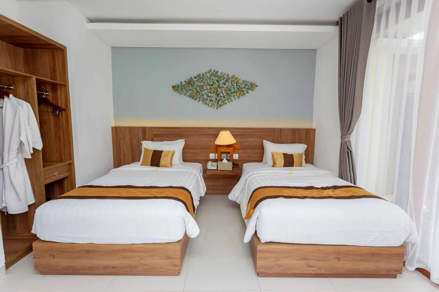 Spacious tropical villa interior with wooden dining table, cushioned sofa, ceiling fan, round mirror, and open deck. - Bali Villas