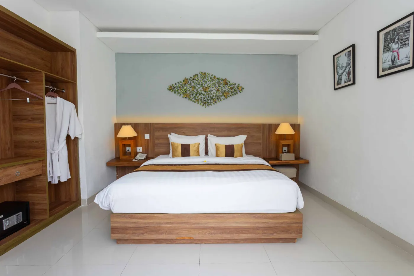 Spacious tropical villa interior with wooden dining table, cushioned sofa, ceiling fan, round mirror, and open deck. - Bali Villas