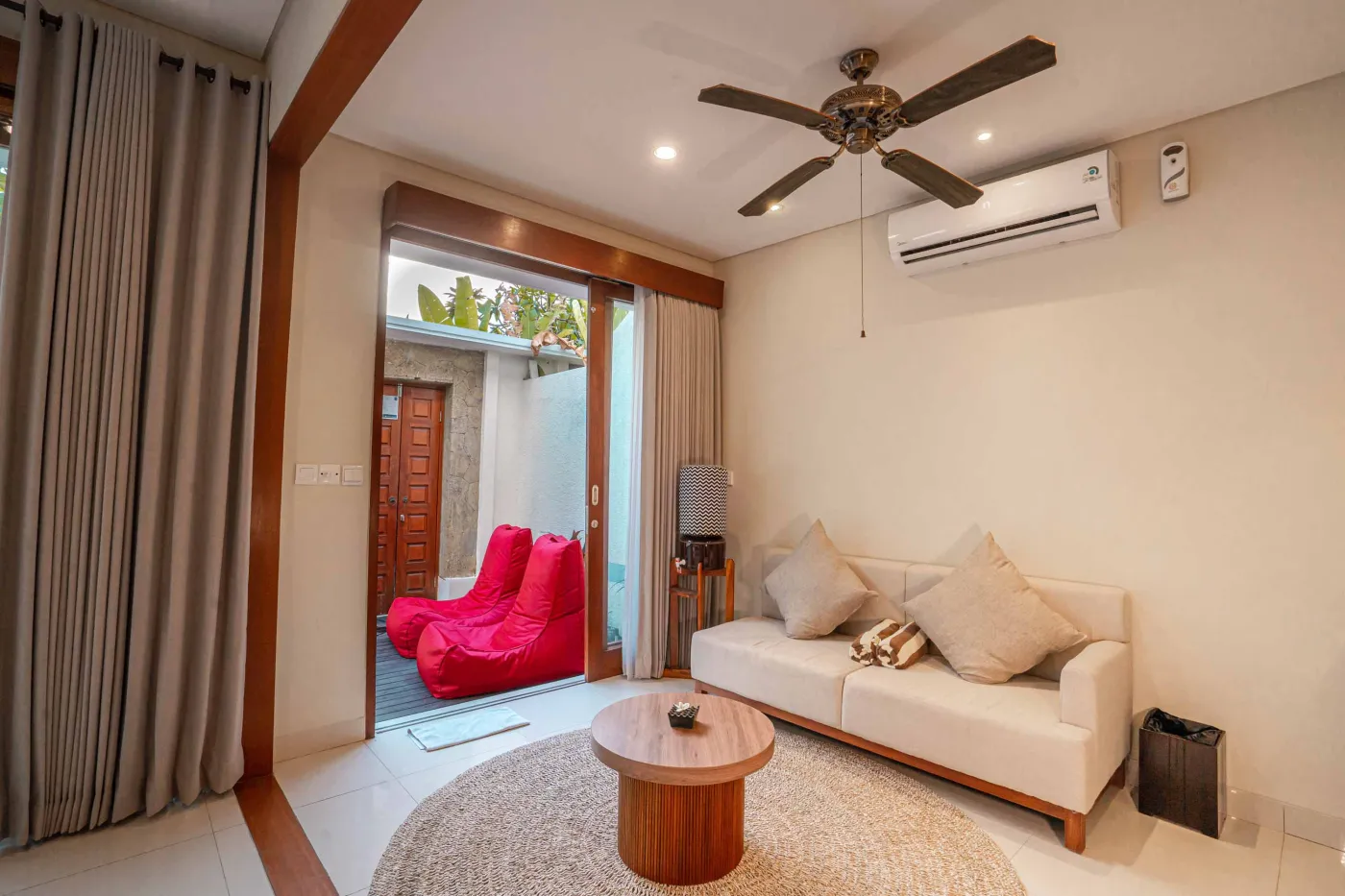 Luxurious Bali pool villa with private plunge pool, red bean bag chairs, and open doors to a rose petal-adorned bedroom. - Bali Villas