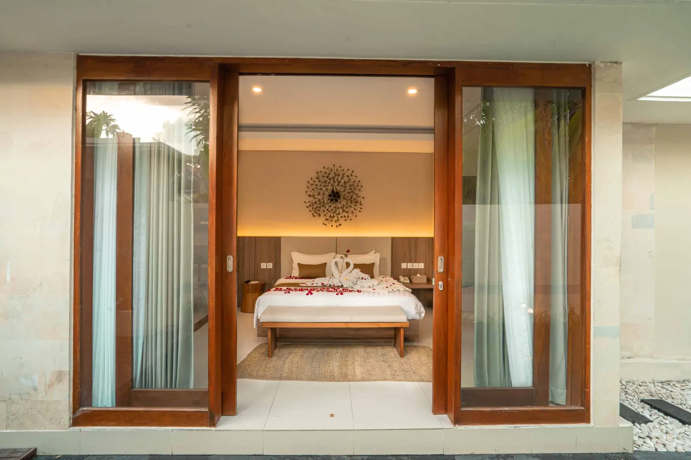 Luxurious Bali pool villa with private plunge pool, red bean bag chairs, and open doors to a rose petal-adorned bedroom. - Bali Villas