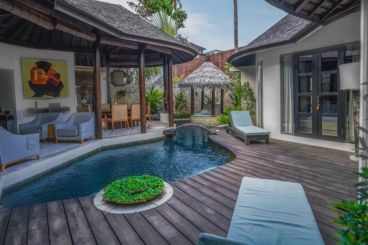 Luxury tropical villa patio with infinity pool, wooden deck, lounge chairs, and lush greenery. - Bali Villas