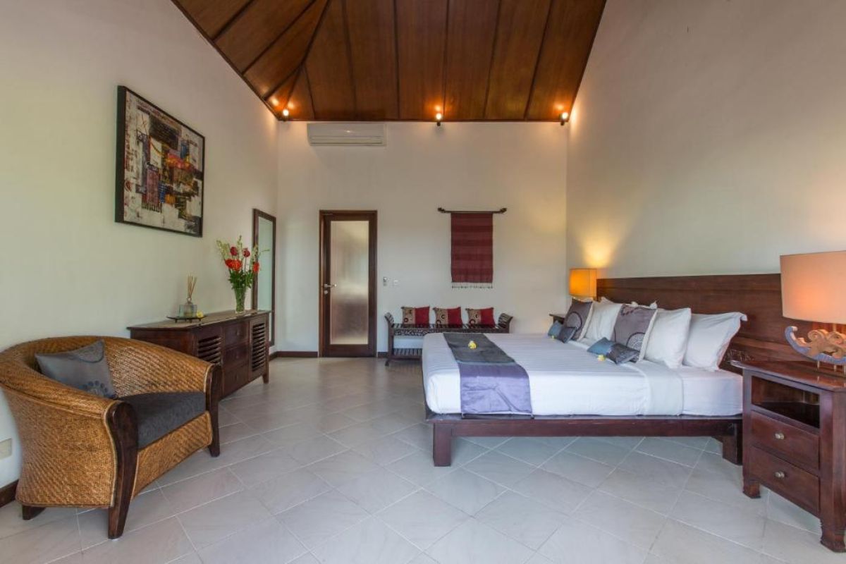 Modern wooden bathroom vanity with rattan accents, double sink, mirror, towels, and tropical decor. - Bali Villas