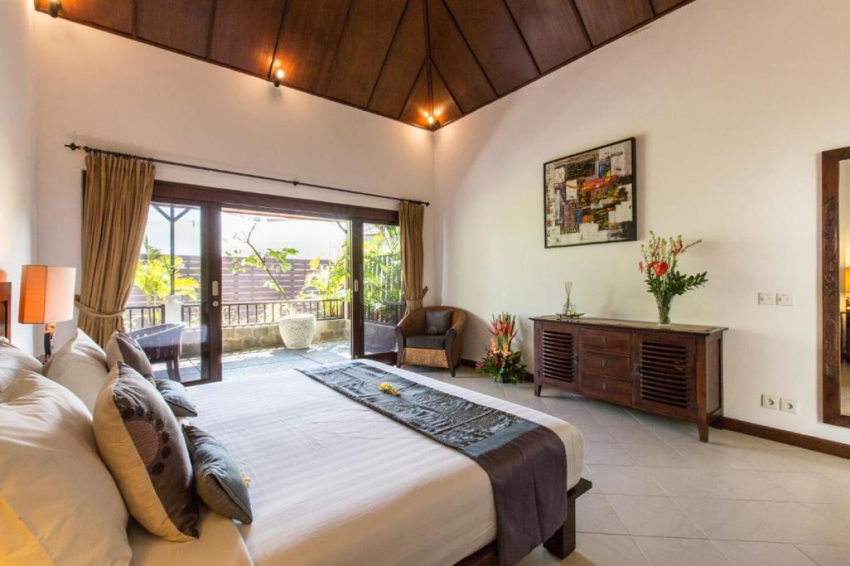 Modern wooden bathroom vanity with rattan accents, double sink, mirror, towels, and tropical decor. - Bali Villas