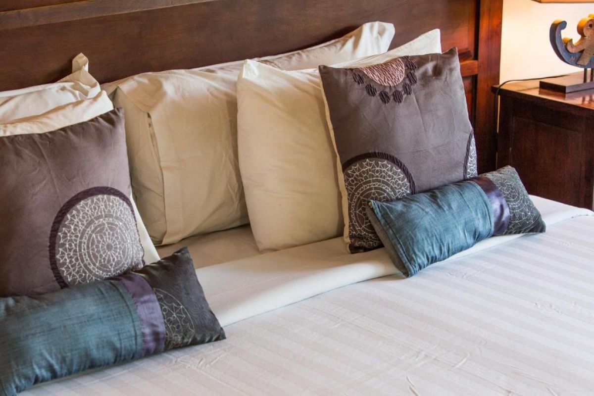 Modern wooden bathroom vanity with rattan accents, double sink, mirror, towels, and tropical decor. - Bali Villas