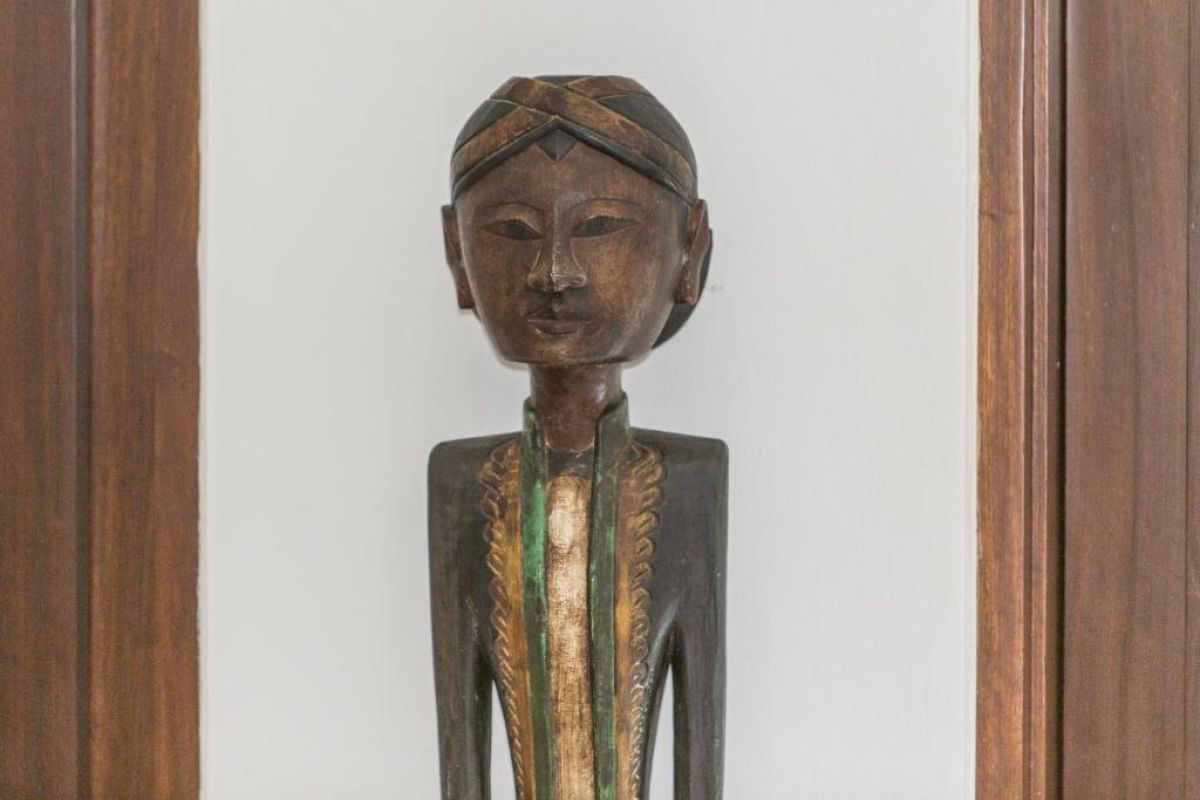 Modern wooden bathroom vanity with rattan accents, double sink, mirror, towels, and tropical decor. - Bali Villas