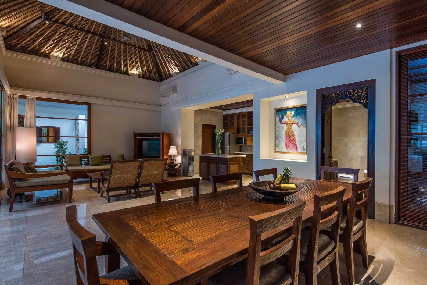 Luxurious tropical bathroom featuring a freestanding white bathtub, wooden vanity with double sinks, large mirror, and open door to lush greenery. - Bali Villas