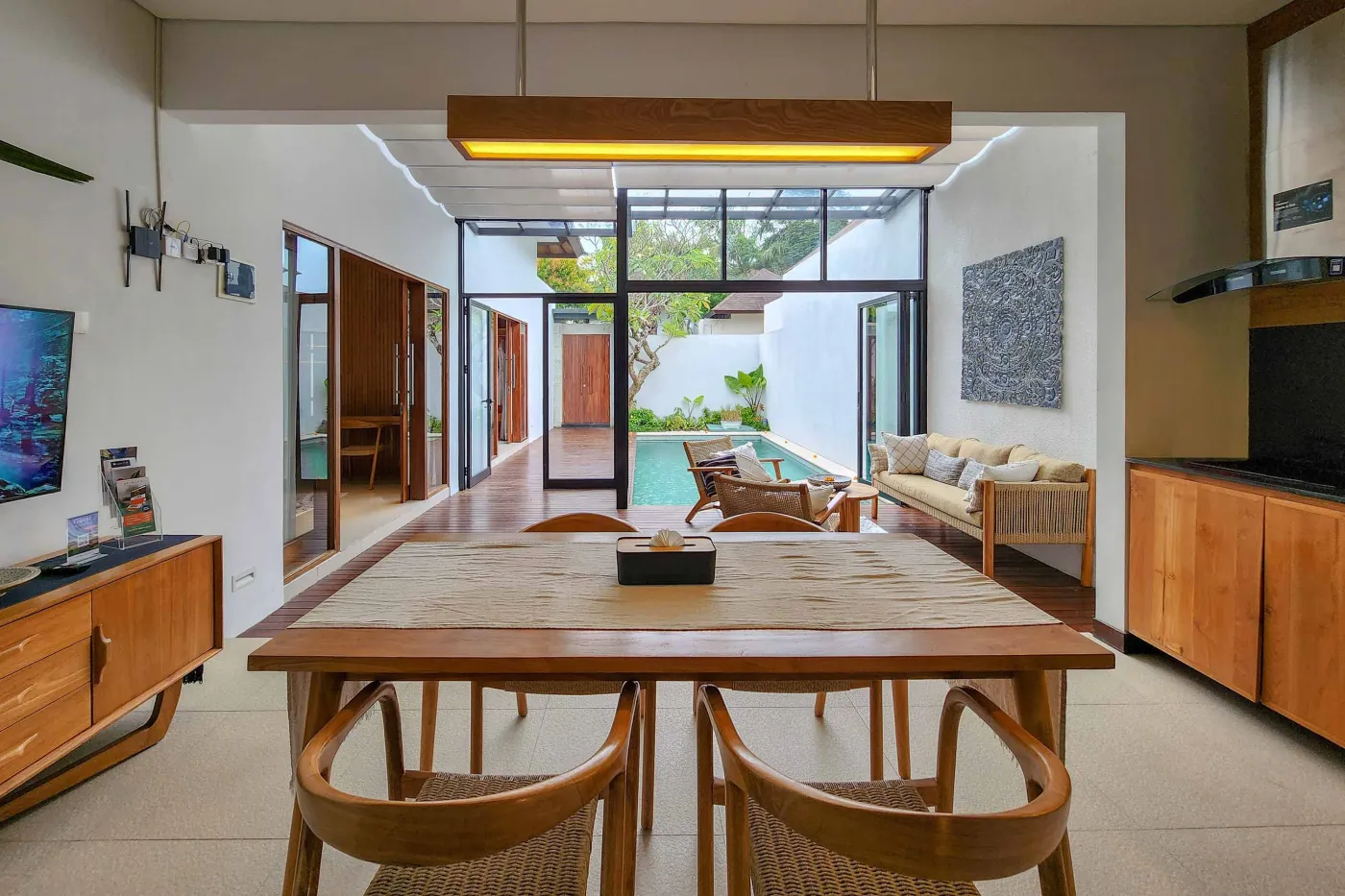 Modern luxury bathroom featuring a freestanding white bathtub, wooden vanity with towels and plants, and bamboo towel rack against neutral walls. - Bali Villas