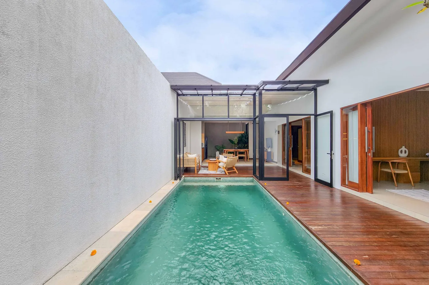 Modern luxury bathroom featuring a freestanding white bathtub, wooden vanity with towels and plants, and bamboo towel rack against neutral walls. - Bali Villas