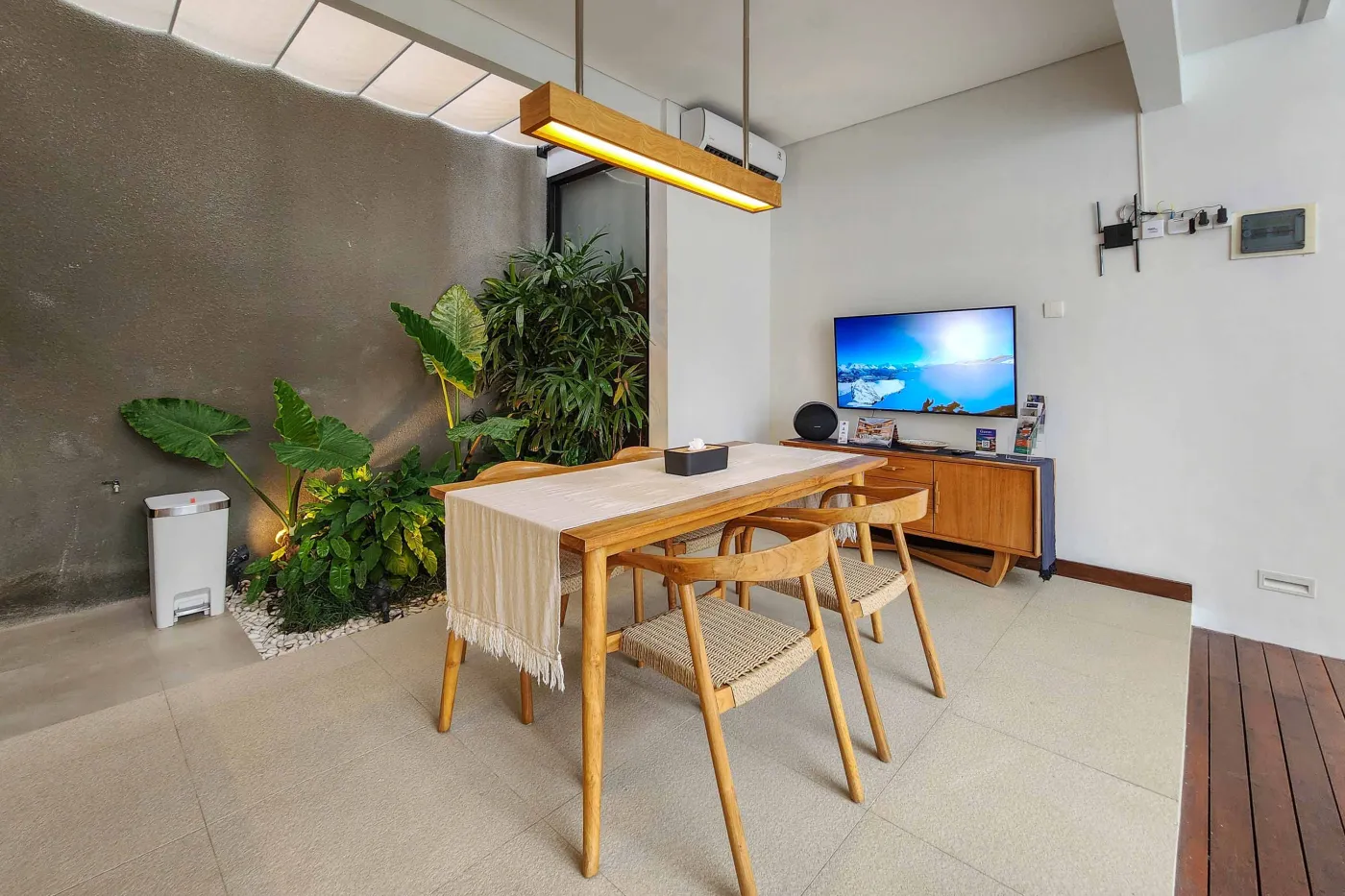 Modern luxury bathroom featuring a freestanding white bathtub, wooden vanity with towels and plants, and bamboo towel rack against neutral walls. - Bali Villas