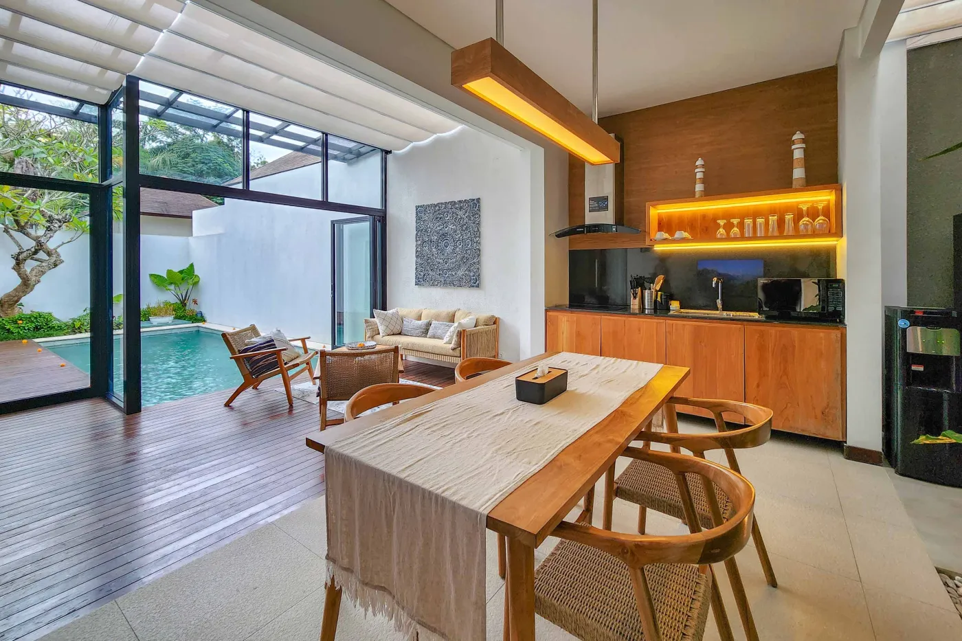 Modern luxury bathroom featuring a freestanding white bathtub, wooden vanity with towels and plants, and bamboo towel rack against neutral walls. - Bali Villas