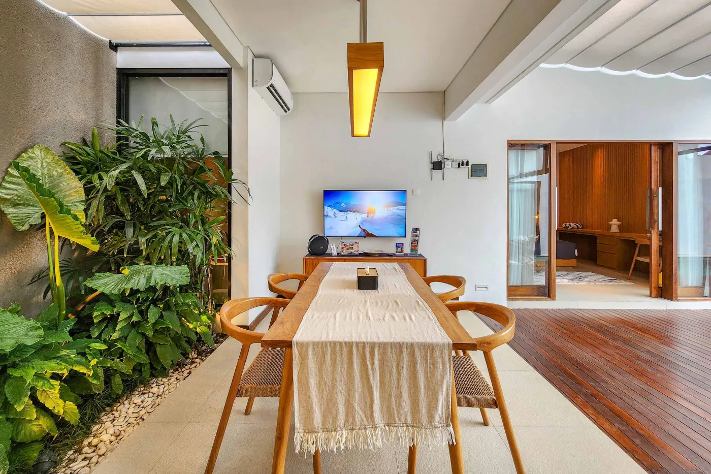 Modern luxury bathroom featuring a freestanding white bathtub, wooden vanity with towels and plants, and bamboo towel rack against neutral walls. - Bali Villas