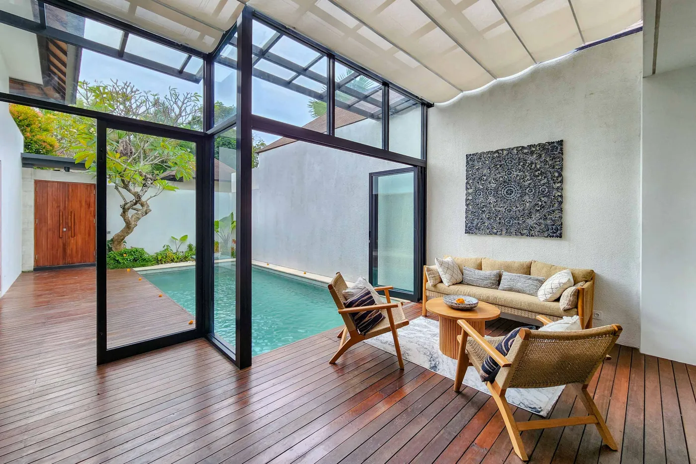 Modern luxury bathroom featuring a freestanding white bathtub, wooden vanity with towels and plants, and bamboo towel rack against neutral walls. - Bali Villas